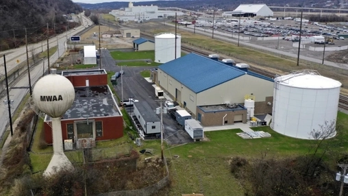 Aerial view of a water utility facility with an MWAA water tower, storage tanks, and industrial buildings