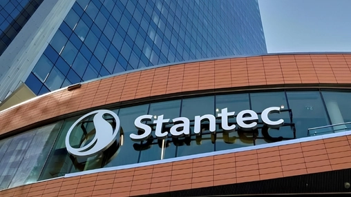 lose-up of the Stantec logo mounted on a curved glass and terracotta-clad commercial building exterior