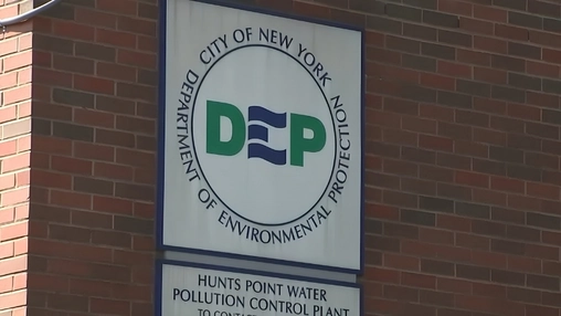 Circular DEP logo sign and Hunts Point Water Pollution Control Plant name plate on a brick wall exterior