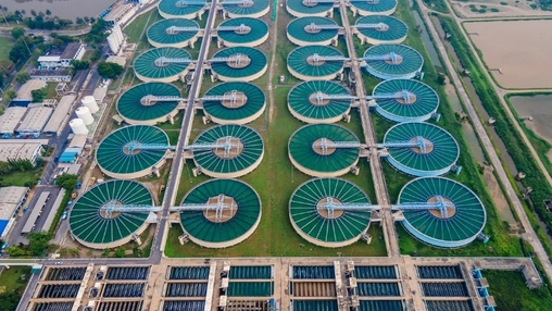 Overhead view of circular clarifiers with radial scraper arms and rectangular basins at a treatment facility