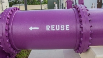 Purple pipe stenciled with REUSE and a directional arrow at a water reuse facility