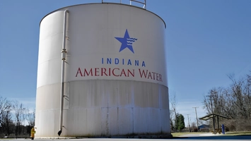 Large cylindrical water tank branded with the Indiana American Water logo photographed against a blue sky