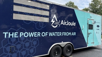 Navy and teal AirJoule Technologies trailer with GE Vernova and Carrier branding parked outdoors among trees