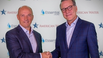 Two executives in blue suits shake hands in front of an American Water and Essential Utilities backdrop