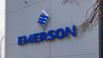 Close-up of the Emerson corporate sign on a grey exterior wall, with the blue diamond logo above the wordmark